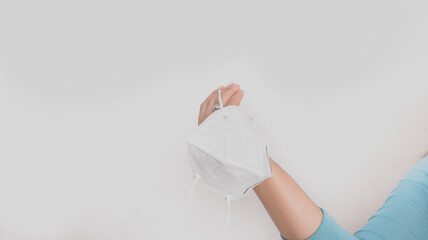 Hand with a ring, holding a face mask, to prevent the spread of diseases or viruses.