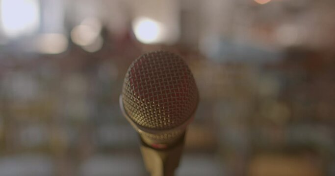 Close-up of a microphone grid. Protection of the broadcasting device in the reproduction of the voice of the host of the event. Background in bokeh. Handheld shooting.