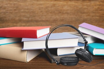 Audio book concept. Headphones and book on wooden table