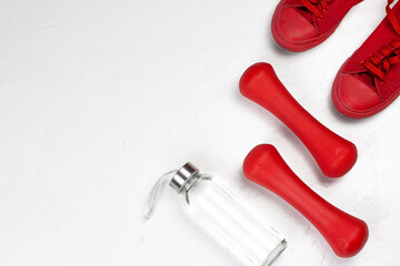 Sport and healthy lifestyle concept. Red sneakers, dumbbells and bottle of water on white background flat lay image. Fitness equipment minimal concept.