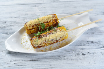 grilled corn on the cob with parmesan cheese and sprouts
