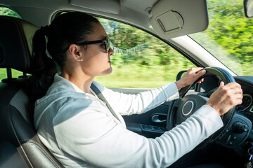 Condutora concentrada com as mão no volante a conduzir o carro enquanto viaja