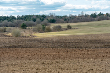 Obraz premium beautiful rural landscape. Hilly plowed agricultural fields against the background of clouds. The play of light and shadow on a hilly landscape.
