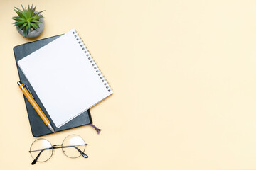 Black blank notebook, pen, glasses, goggles top view on beige background. Top view desk arrangement. Time management, planning concept. Minimal style, mock up with copy space, template logo design