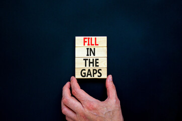 Fill in the gaps symbol. Concept words Fill in the gaps on wooden blocks on a beautiful black table black background. Businessman hand. Business, motivational and fill in the gaps concept.