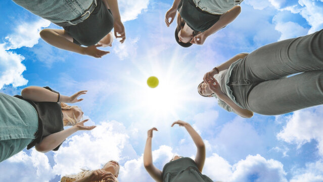 Girlfriends throw the ball to each other against the blue sky.