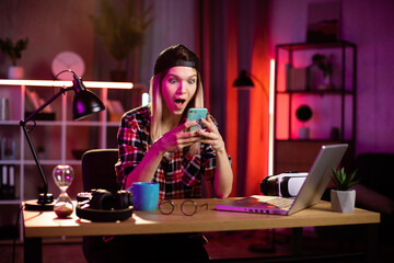 Overjoyed caucasian woman looking at mobile screen and gesturing emotionally. Young girl reading good news on mobile. Concept of success, victory and happy moments.