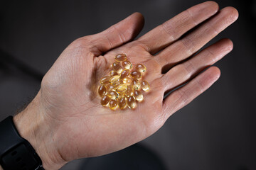 vitamin d medicinal fish oil capsules in the palm of your hand.