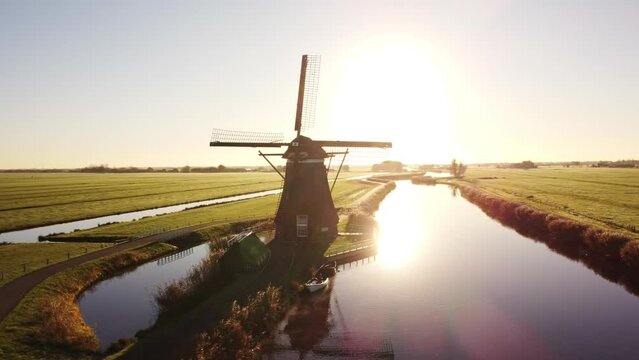 Aerial drone footage of a Dutch windmill in the countryside by sunrise. Circle around shot.