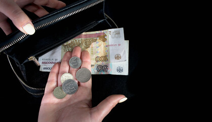Russian rubles bills and coins in a black wallet in a man's hand on a black background