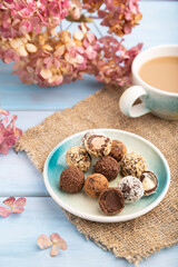 Chocolate truffle candies with cup of coffee on a blue wooden background. side view, close up, selective focus.