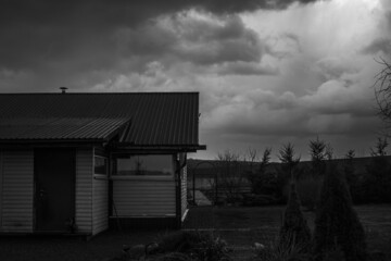 House and part of the yard in cloudy weather. black and white
