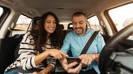 Happy couple driving car and using cell phone