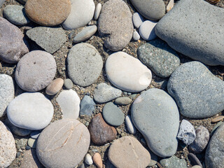 Background from multicolored pebbles. Black sand. Pebble coast. Stone beach. Stone pattern.