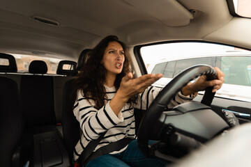 Angry woman driving car shouting at somebody