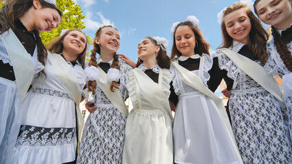 Smiling female graduates pose on the last day of school life.