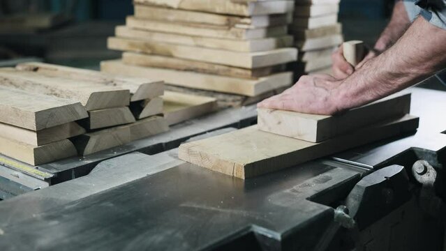 Close-up of hands and wood workpiece on planer. An unrecognizable man works as a carpenter.