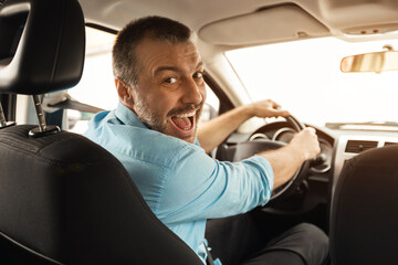 Smiling man driving new car in city