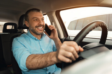 Happy man talking on smartphone while driving car
