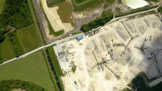 Aerial view of sand quarry, industrial extraction of a sand for construction industry. Excavators and tractors load crushed stone and rock into dump trucks. 4K. Separation of sand in construction. 