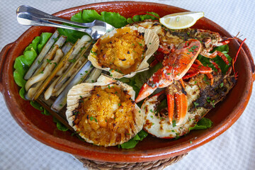 Clay pot with assorted seafood (scallops, razor clams, lobster) on the table 
