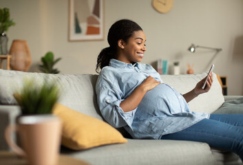 Cheerful Pregnant African Lady Using Smartphone Video Calling At Home - obrazy, fototapety, plakaty