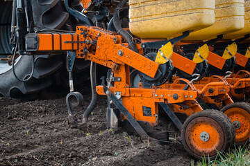 A tractor with a seed drill is engaged in planting corn. Close-up of the seed drill. Field work.