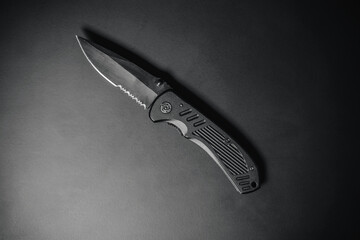 Close up detail photo of a combat folding knife. Product design photo of an army or SWAT knife. Sharp concealed carry knife. Every day carry knife on black background.