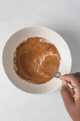 Cinnamon powder sprinkled on milk in a white bowl