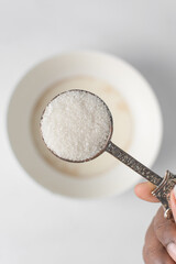 A tablespoon of white sugar, granulated sugar in a spoon