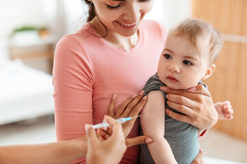Vaccination concept. Pediatrician doctor giving vaccine shot to little baby at home, making...