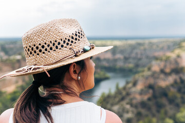 Woman observing the gorges of the Duraton River with her hat. Close up shot of a young girl dressed...
