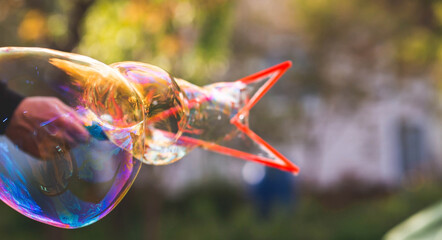 A man's hand makes big huge bright soap bubbles against the background of trees. Soap bubble show....