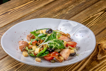 Salmon salad - smoked salmon hard boiled eggs, white cheese and green vegetables on wooden table
