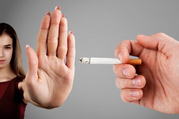 Woman showing stop sign with hand and refusing to take cigarette. No smoking concept