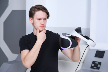 Portrait of pensive sad young handsome man, upset guy using, wearing a modern device virtual...