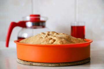 Making apple pie at home. Homemade pastry in silicone cake pan served with cherry fruit drink