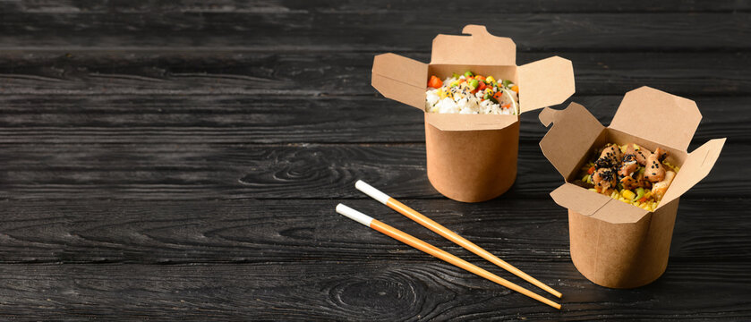 Boxes with tasty Asian rice on dark wooden background with space for text