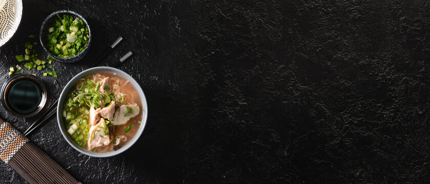 Bowl of tasty Chinese soup on dark background with space for text