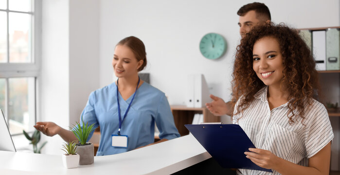 Young African-American woman near reception desk in clinic