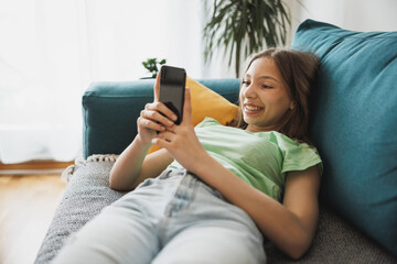 Teen Girl Using Smart Phone While Having Leisure Time At Her Home