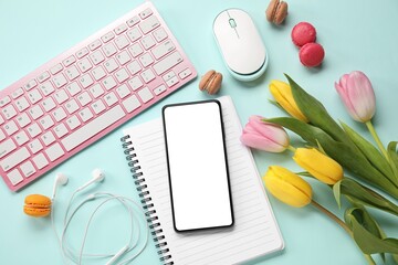 Composition with computer, smartphone, macarons and tulip flowers on light blue background, top view