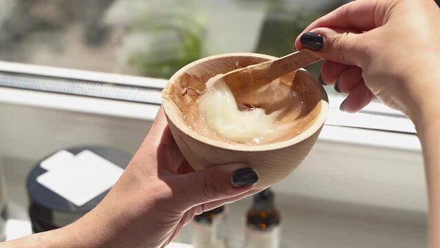 beautician mixes yellow color hair mask in wooden plate
