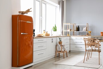 Interior of light modern kitchen with orange fridge