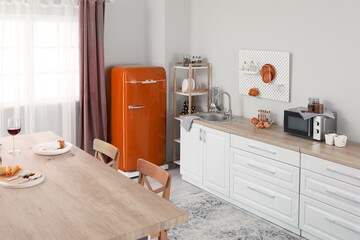 Interior of light kitchen with orange retro fridge