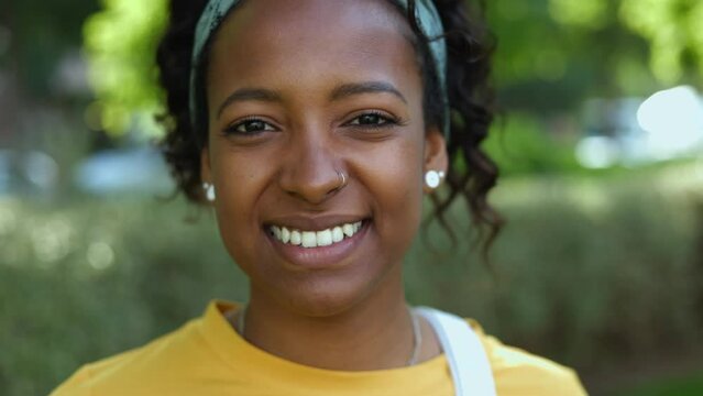 Close up portrait of pretty young african american woman smiling at camera. Happy lifestyle people concept with millennial teenager female student laughing outdoors
