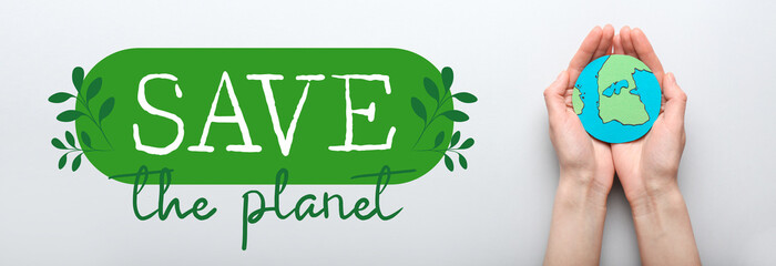 Human hands with paper Earth on light background. Save the planet