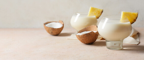 Glasses of tasty Pina Colada cocktail on light background with space for text