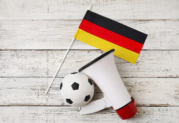 Fototapeta premium Flag of Germany, bullhorn and soccer ball on light wooden background