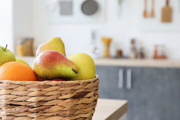 Wicker basket with fresh fruits in modern kitchen, closeup